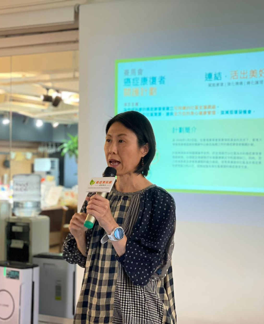 藍詠德教授拿著麥克風介紹賽馬會癌症康復者關護計劃。