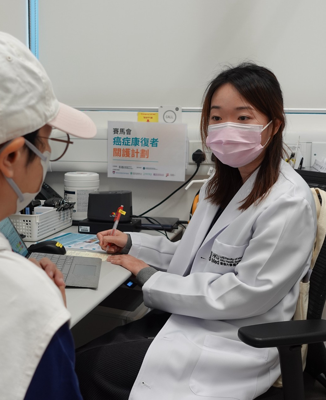 A healthcare professional from the Jockey Club Cancer Care for Survivors Project wearing a mask conducts a professional assessment with a patient.