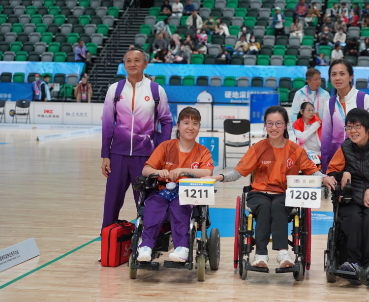 Sharing a proud moment on court, Karen Kwok smiles for a photo in her wheelchair beside her coach in their team uniform.